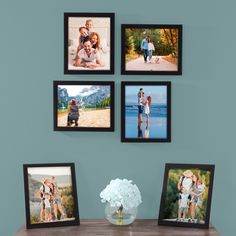 four framed photos hang on the wall above a table with a vase and white flowers