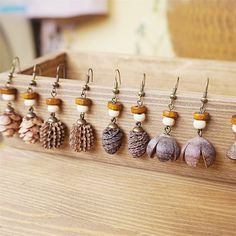 there are many different types of earrings hanging on a rack with pine cones and acorns