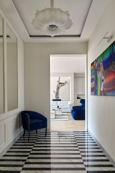 a hallway with black and white checkered flooring next to a painting on the wall