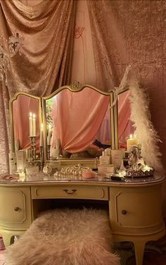 a vanity with a mirror, stool and candles