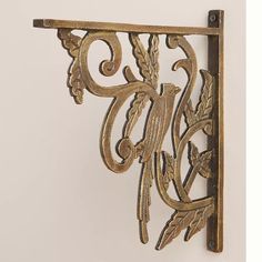 an ornate metal shelf bracket on the wall with leaves and scrolls attached to it's sides