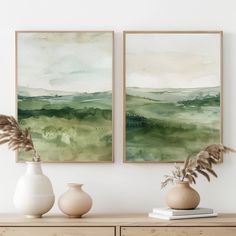 two vases with plants sit on a dresser in front of the wall above them