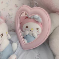 two stuffed animals sitting next to each other on a bed with a heart shaped mirror