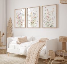 a white bedroom with three paintings on the wall