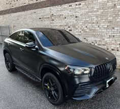 a black mercedes suv parked in front of a brick wall