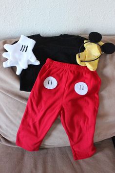 two mickey mouse outfits are laying on a bed