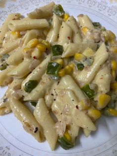 a white plate topped with pasta and corn