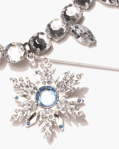 a snowflake brooch is shown on a white surface with blue and clear stones