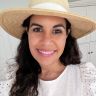 a woman wearing a white hat and smiling for the camera with long hair in front of her face