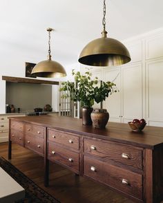 a kitchen with two lights hanging over it's counter top and an island in the middle