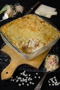 a casserole dish on a wooden cutting board with spoons next to it