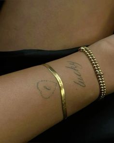 a woman's arm with a gold bracelet and name written on it, in cursive writing