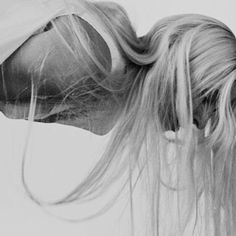 a black and white photo of a woman with her hair blowing in the wind