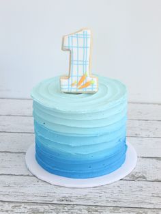 a blue and white cake with the number one frosted on it's top