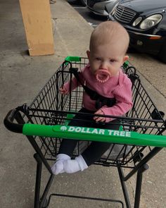 a baby sitting in a shopping cart with dollar tree written on it