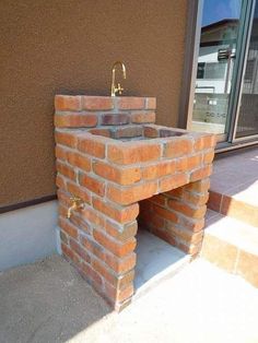 an outdoor sink made out of bricks on the side of a building next to a window