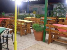 an outdoor dining area with tables and chairs, lights on the roof and potted plants