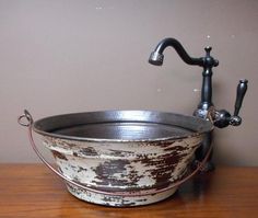 an old metal bucket sitting on top of a wooden table next to a faucet