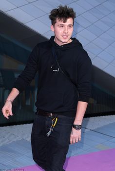 a man in black hoodie walking on purple carpet