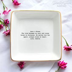 a white and gold plate with pink flowers in the background