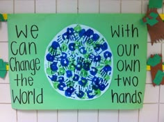 we can change the world with our own hands on a green sign in front of a white brick wall