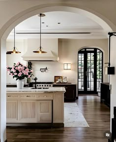 an archway leads to the kitchen and dining room in this modern home with wood flooring