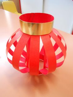 a red vase sitting on top of a table covered in paper and gold trimmings