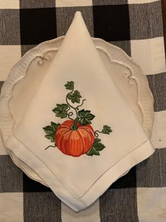 a white plate topped with a pumpkin on top of a checkered table cloth