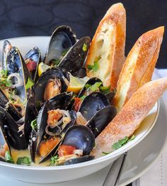 a white bowl filled with mussels and bread