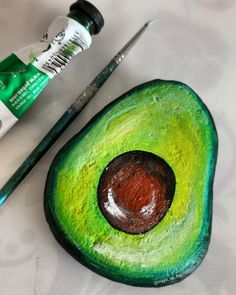 an avocado painted with acrylic paint next to a pair of scissors