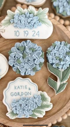 cookies decorated with blue flowers are on a wooden platter for guests to sit in