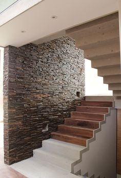 a stone wall next to some stairs in a house