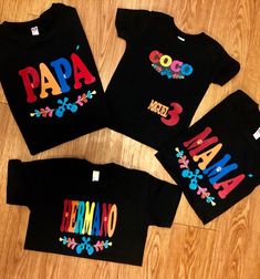 three black shirts with colorful letters and flowers on the front, one is for mom and two are for baby