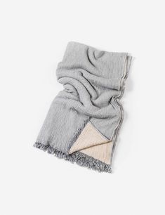 the grey and beige scarf is folded on top of a white surface, with two different colors