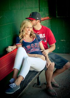 a man and woman sitting on a red bench in front of a green brick wall