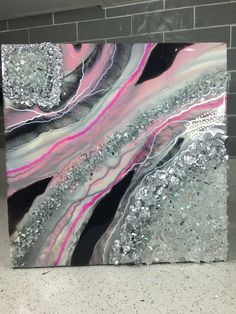 an abstract painting with silver, pink and black colors on a brick wall in a room