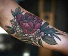 a woman's arm with flowers and leaves on it