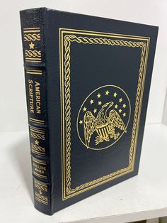 a black and gold book sitting on top of a white table