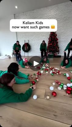 a group of people sitting on the floor in front of a christmas tree playing with toys