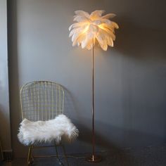 a floor lamp with a white feather shade on it next to a chair and rug