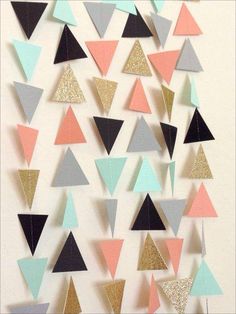 a white wall with many different colored triangles hanging from it's sides and some gold glitter