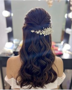 the back of a woman's head with long hair and flowers in her hair