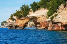 an arch in the rock formation on the coast of lake michigan, with trees around it