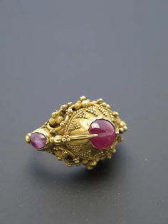 For Sale on 1stDibs - Finely worked in high karat gold (22k+) and featuring three rough cut ruby cabochons ranging form light pink to purplish pink, typical of rubies from Indonesia. Yellow Gold Gemstone Temple Ring, Yellow Gold Gemstone Temple Jewelry Ring, Yellow Gold Gemstone Ring In Temple Jewelry Style, Yellow Gold Temple Jewelry Ring With Gemstone, Gold Ruby Rings With Intricate Design, Traditional Ruby Ring In Yellow Gold, Traditional Gold Oval Ruby Ring, Traditional Oval Ruby Ring In Gold, Yellow Gold 22k Ruby Wedding Ring