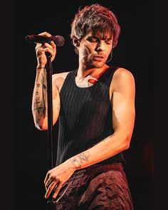 a man with tattoos on his arm holding a microphone