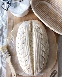 a loaf of bread sitting on top of a wooden cutting board next to a brush