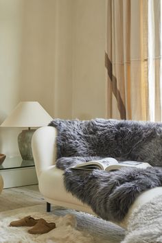 a chair with a book on it in front of a window and a lamp next to it