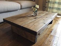 a wooden coffee table sitting on top of a hard wood floor next to a couch