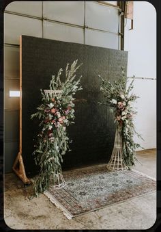 two tall floral arrangements on display in front of a black backdrop with white and pink flowers