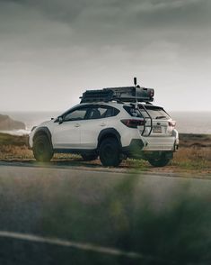 a white car parked on the side of a road next to a body of water